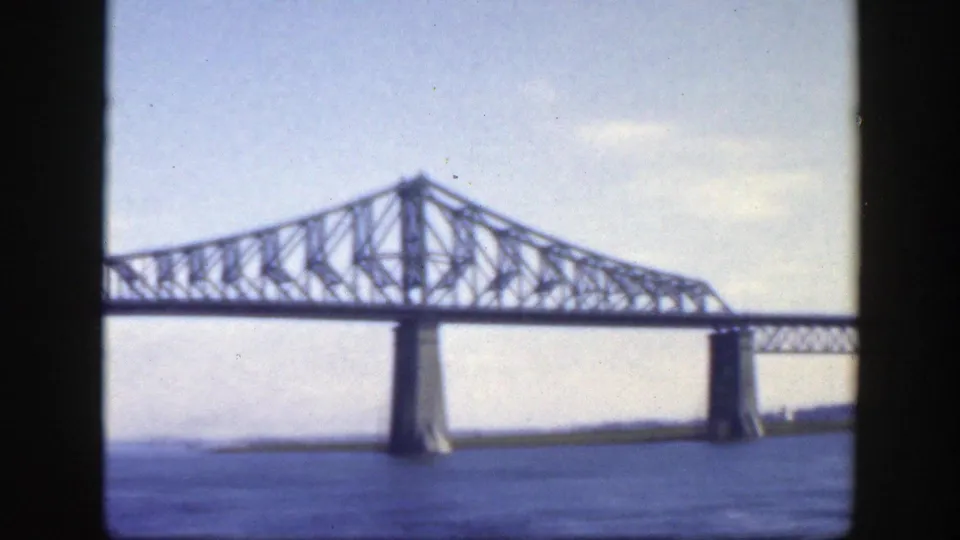 Water-level view of the Jacques-Cartier Bridge structure in Montreal, with the truss and concrete pier filling the frame.