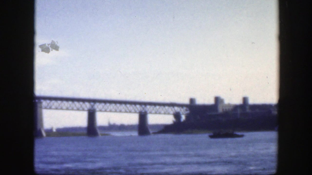 1950 Montreal 8mm frame with bridge latticework, concrete supports, river surface, and distant waterfront buildings.
