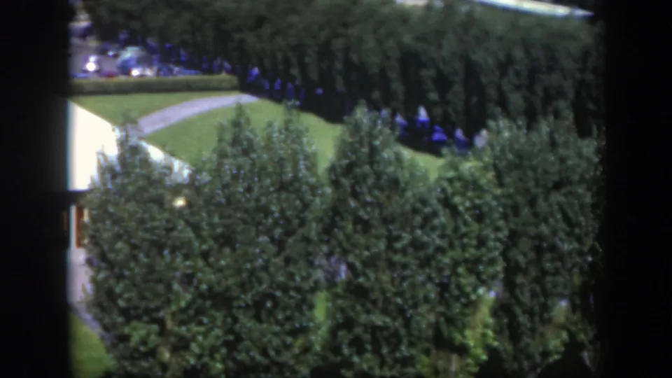 1950 Montreal 8mm frame with dense trees, a curved path, lawn, and part of a white-roofed building.