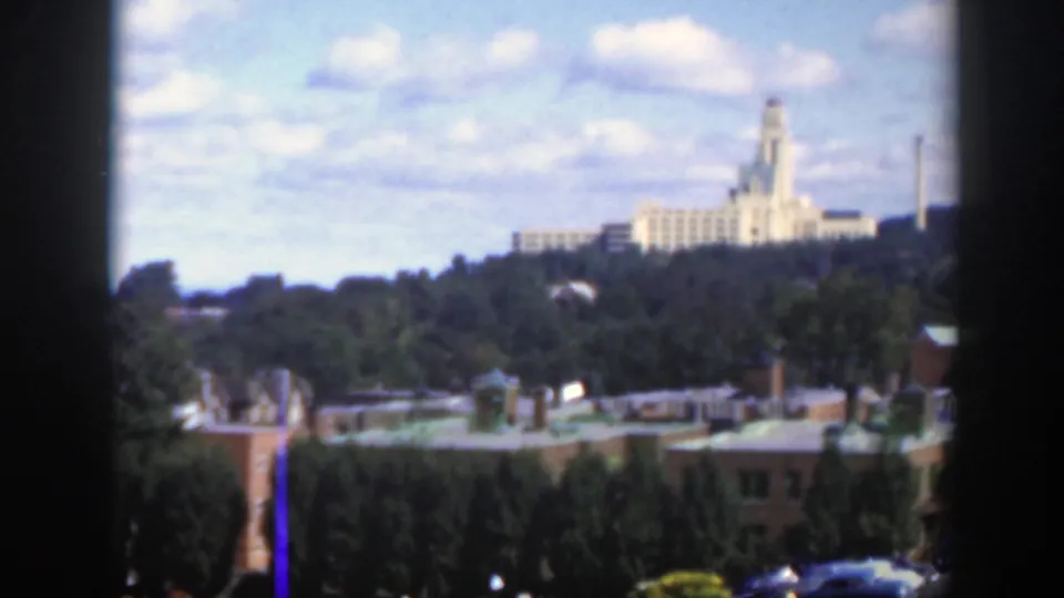 1950 Montreal 8mm skyline view with a prominent hilltop building, trees, rooftops, and blue sky.