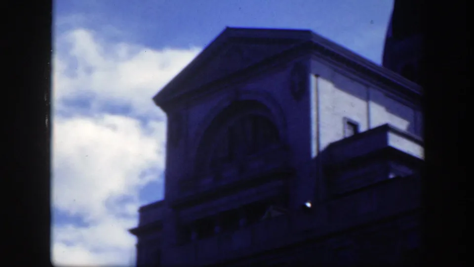 1950 Montreal close-up of a classical stone building facade with arched details and deep shadow from the 8mm exposure.