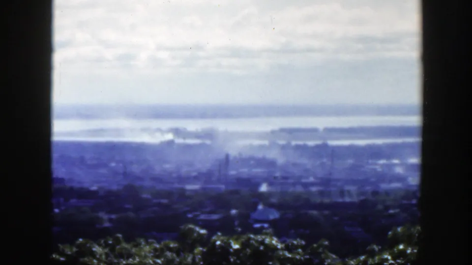 Elevated 1950s Montreal view with soft focus, showing the city, distant water, and a dark vertical divider in the foreground.