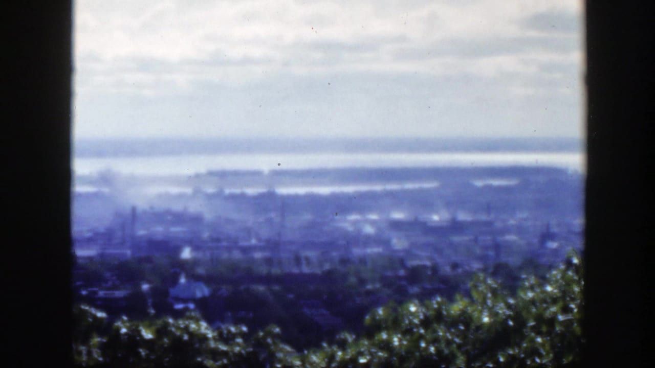 1950 Montreal cityscape and water viewed from an elevated lookout through dark window-like framing.