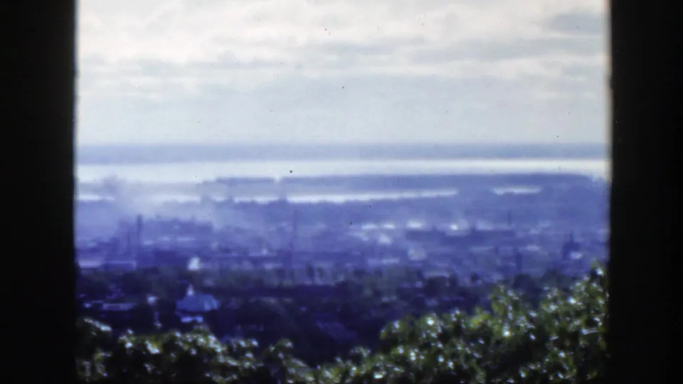 1950 Montreal cityscape and water viewed from an elevated lookout through dark window-like framing.