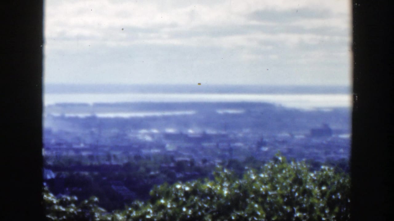 Elevated 1950 Montreal view with water beyond the city, partly obscured by dark foreground framing.