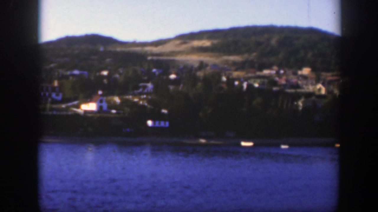 Wide lake view with small boats, shoreline structures and hills.