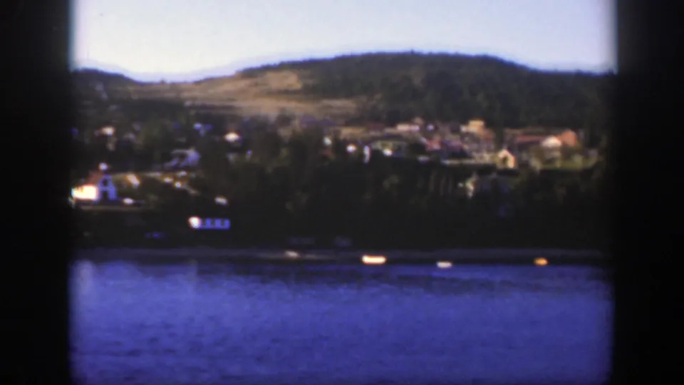 1950 Montreal-area 8mm view of lake water, a distant waterfront town and green hills in soft home-movie color.