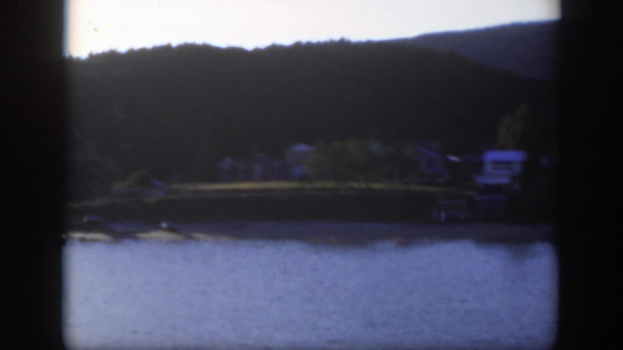 A 1950 Montreal waterfront view shows blue water, trees, and small houses along the far shore.