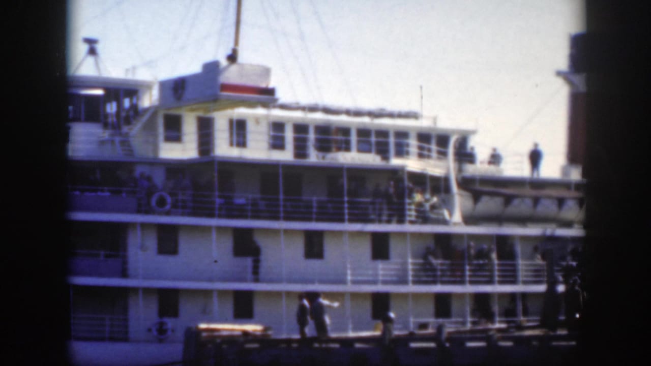 1950 Montreal harbor view of a large white passenger ship with railings, deck figures, rigging, and dark 8mm frame edges.