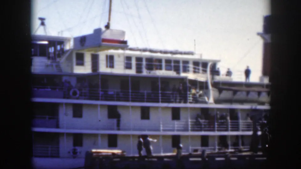1950 Montreal harbor view of a large white passenger ship with railings, deck figures, rigging, and dark 8mm frame edges.