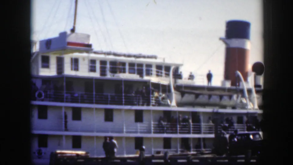 1950 Montreal dock scene with a large passenger ship, red-and-white funnel, distant pedestrians, and a dark car near the pier.