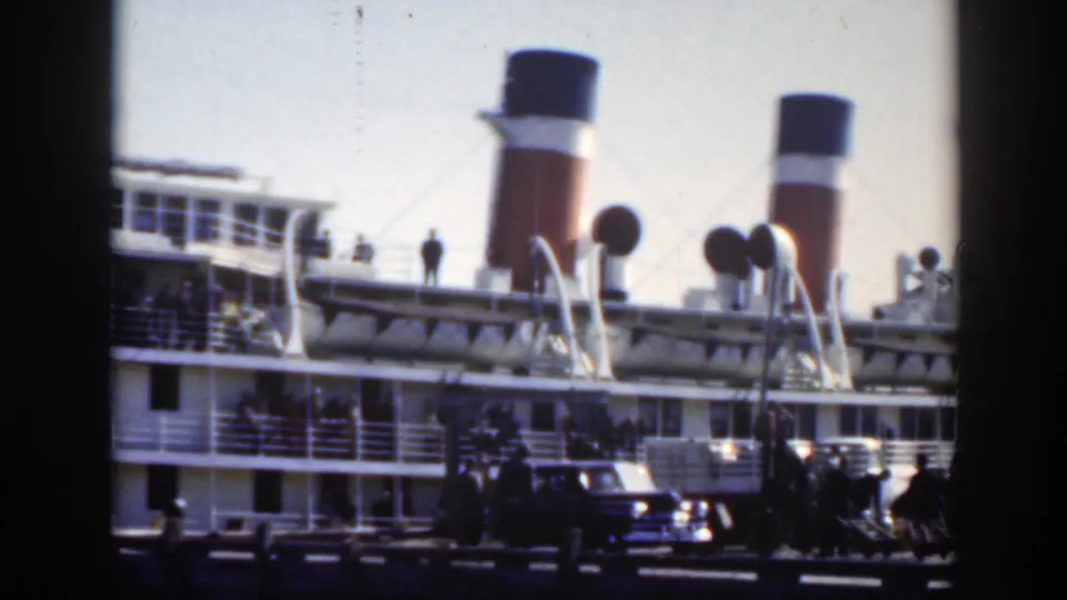 1950 Montreal harbor frame with a large docked passenger ship, red-and-white funnel, distant figures, and a car along the pier.