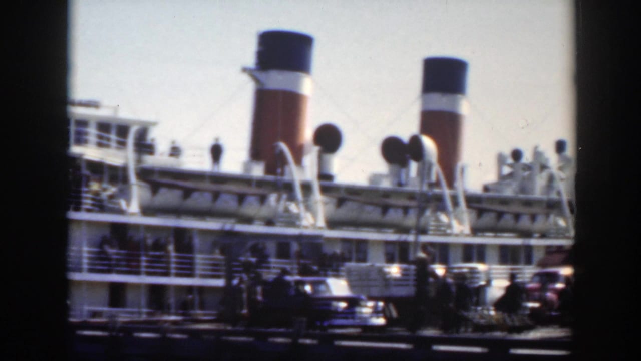 1950 Montreal dockside view of a large passenger ship with twin funnels, deck railings, parked cars, and people near the pier.