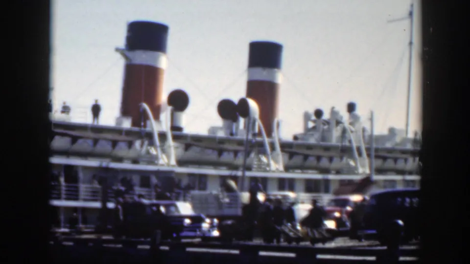 Montreal port scene showing a docked liner, prominent funnels, deck structures, parked automobiles, and small groups of people.