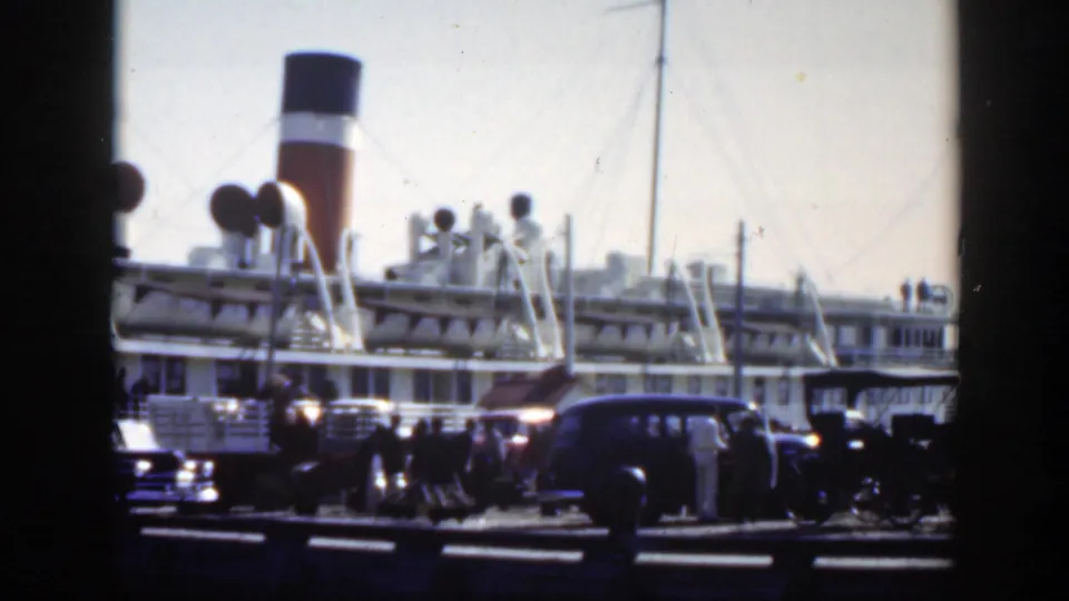 1950 Montreal harbor view of a moored passenger ship, deck structures, nearby automobiles, and pedestrians gathered along the dock.
