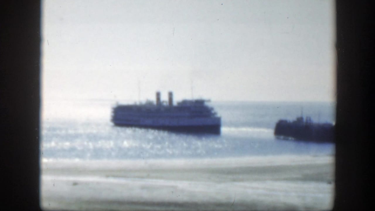 A passenger ship appears offshore in the bright Montreal harbor, with a dark pier or shoreline form at the right edge.