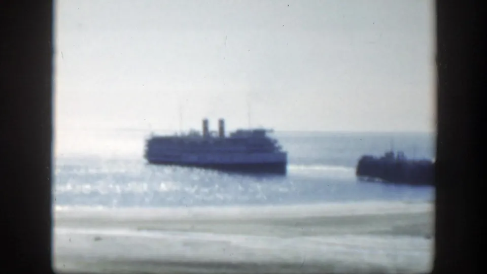 A passenger ship appears offshore in the bright Montreal harbor, with a dark pier or shoreline form at the right edge.