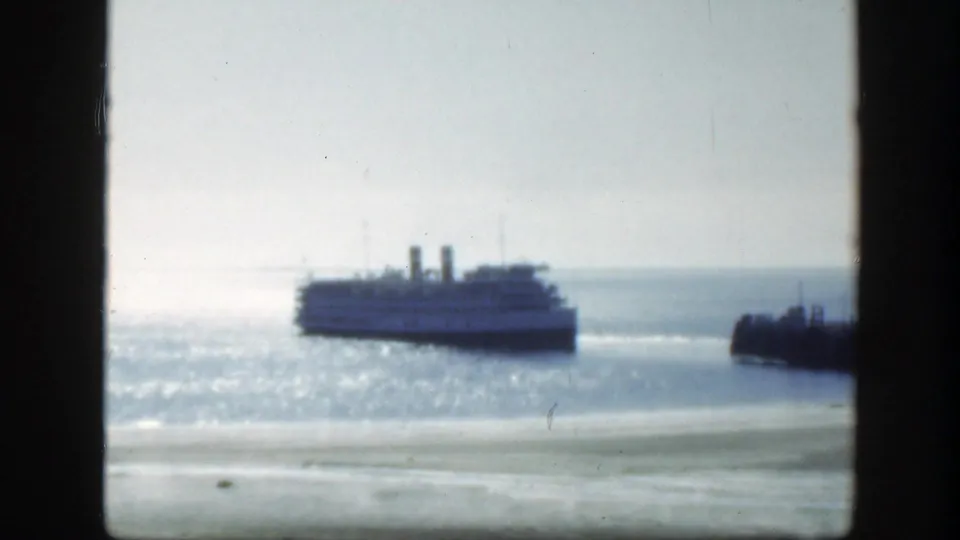 The ship remains offshore in the supplied 1950 Montreal footage, silhouetted softly against glare on the harbor water.