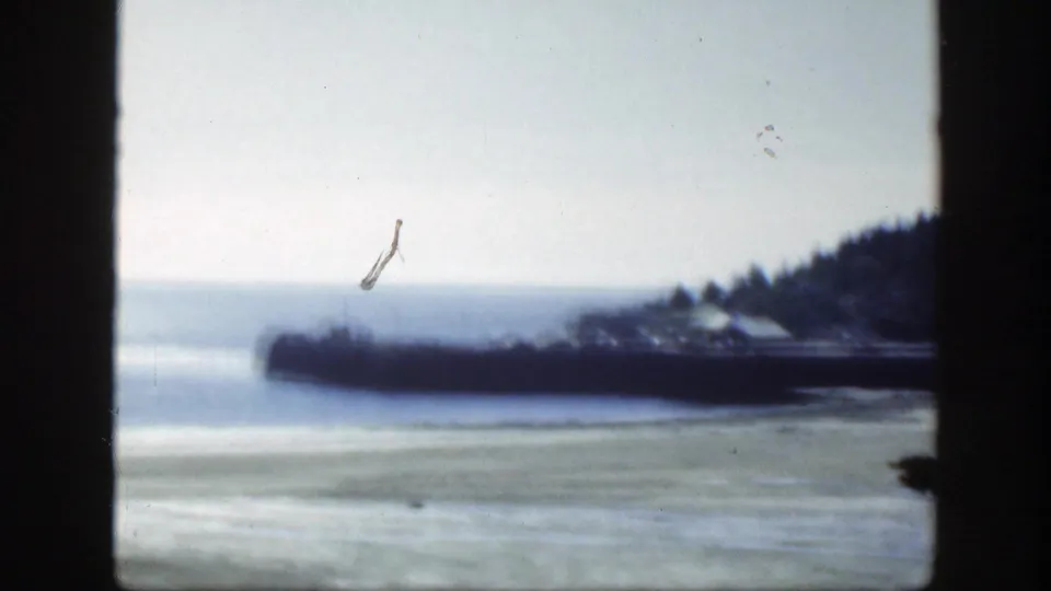 1950 8mm waterfront view near Montreal, with a pier, shoreline trees, and part of a vessel partly obscured by framing.