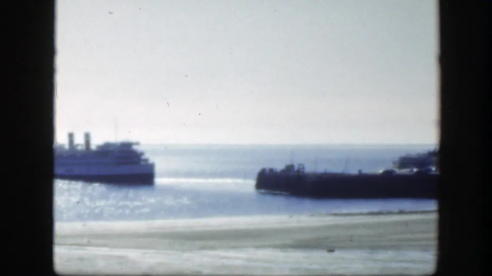 1950 8mm Montreal-area waterfront view with a passenger boat, shimmering water, and dark window framing.
