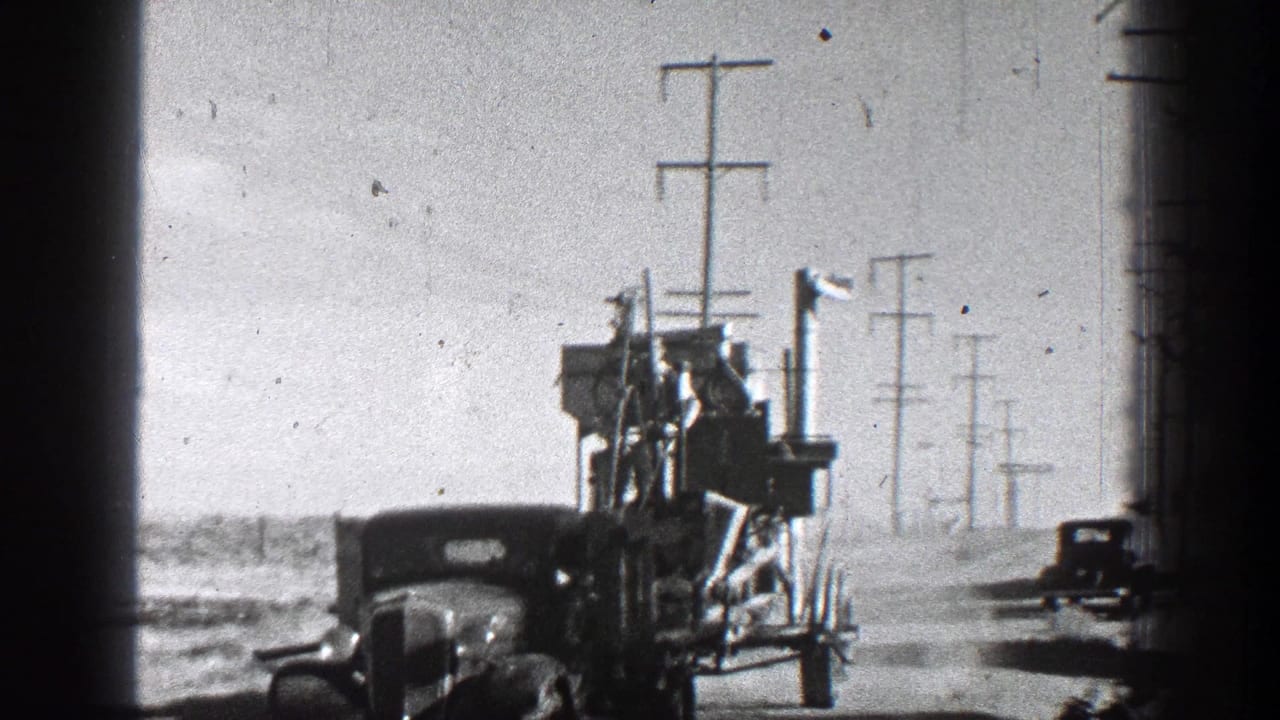 Towed equipment and vehicles move along an open road bordered by utility poles.