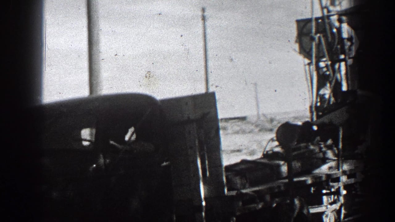 Dark side view of a truck cab and machinery passing beside utility poles.