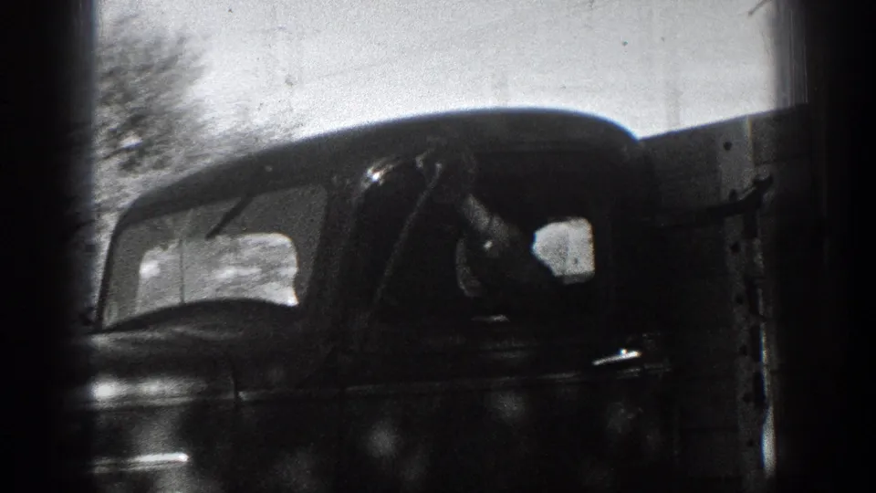 Close 1936 California home-movie view of a vintage truck cab passing, with the driver faintly visible inside.