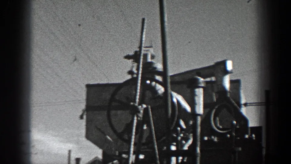 1936 California 8mm frame showing a clearer view of pole-mounted metal equipment, round hardware, supports, and overhead wires.