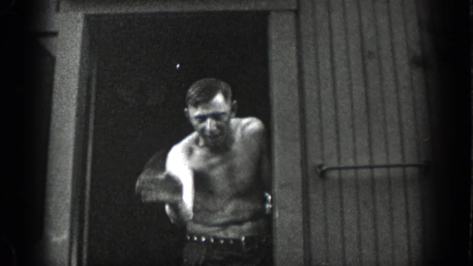 A shirtless adult man stands in a doorway and gestures toward the camera in a candid 1936 California home-movie moment.