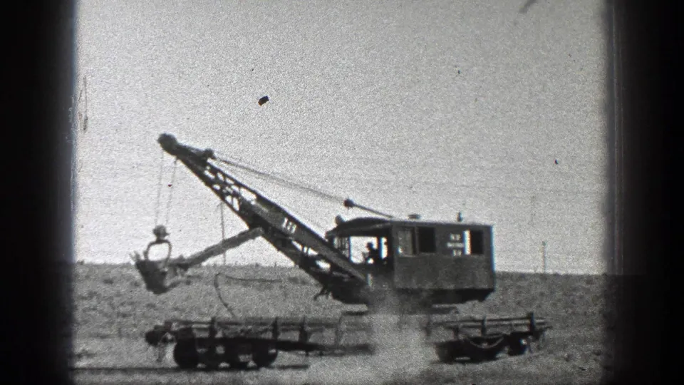 1936 California 8mm frame with an operator visible inside the crane cab and the bucket suspended over open ground.