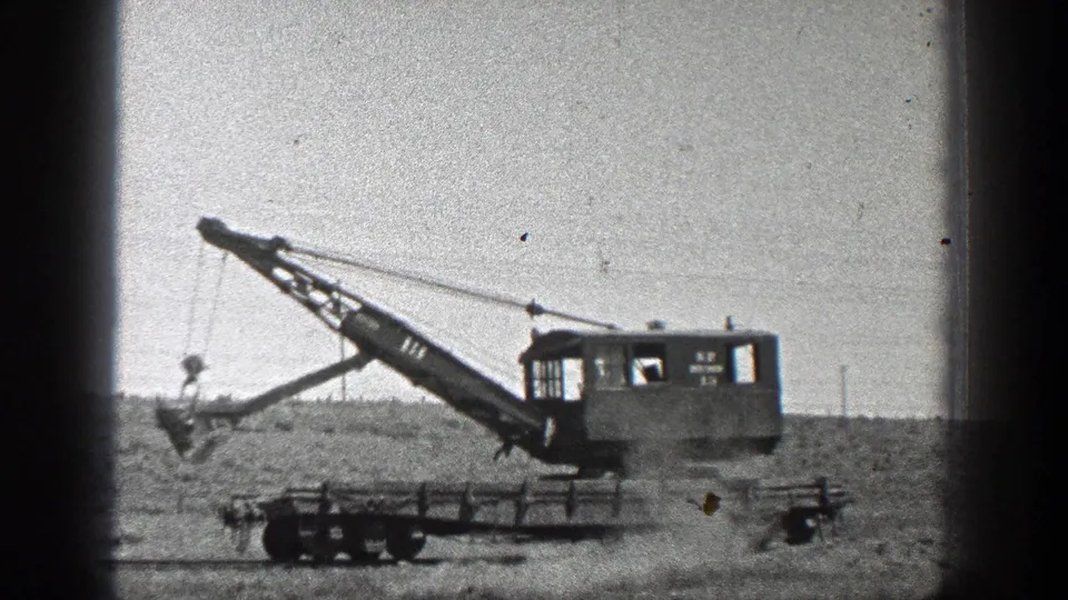 1936 California home-movie frame showing a tracked heavy field machine with an extended boom on open rural ground.