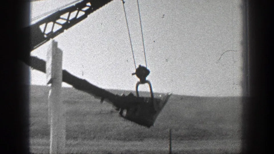 Close 1936 California 8mm view of suspended crane equipment working near railroad construction terrain.