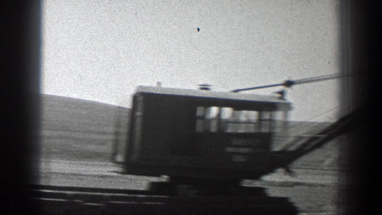 Blurred crane cab and boom moving across an open construction landscape.