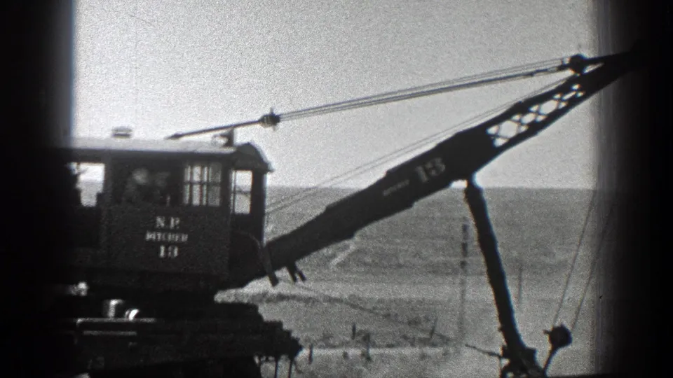 1936 California 8mm frame showing the crane partly cropped as its boom reaches across the open work site.