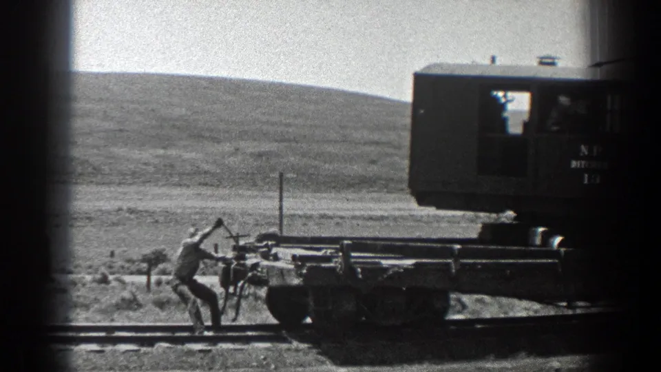 Final 1936 California frame shows the worker bending near the rear of the flat railway car as the rail unit continues past.