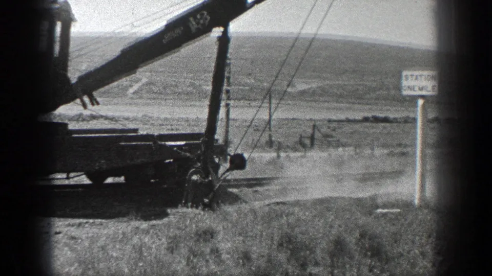 A closer 8mm view shows the crane boom and cable rigging near a sign that appears to read Station One Mile.
