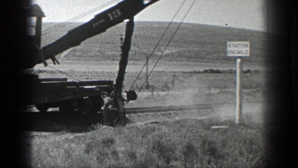 The final frame holds on the crane boom, suspended cables, and station sign against a bright rural California backdrop.