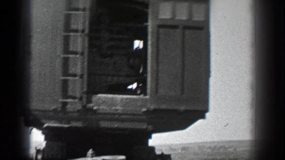 Soft black-and-white frame showing the end platform or cabin of a rail vehicle, partially obscured by motion and frame edge.