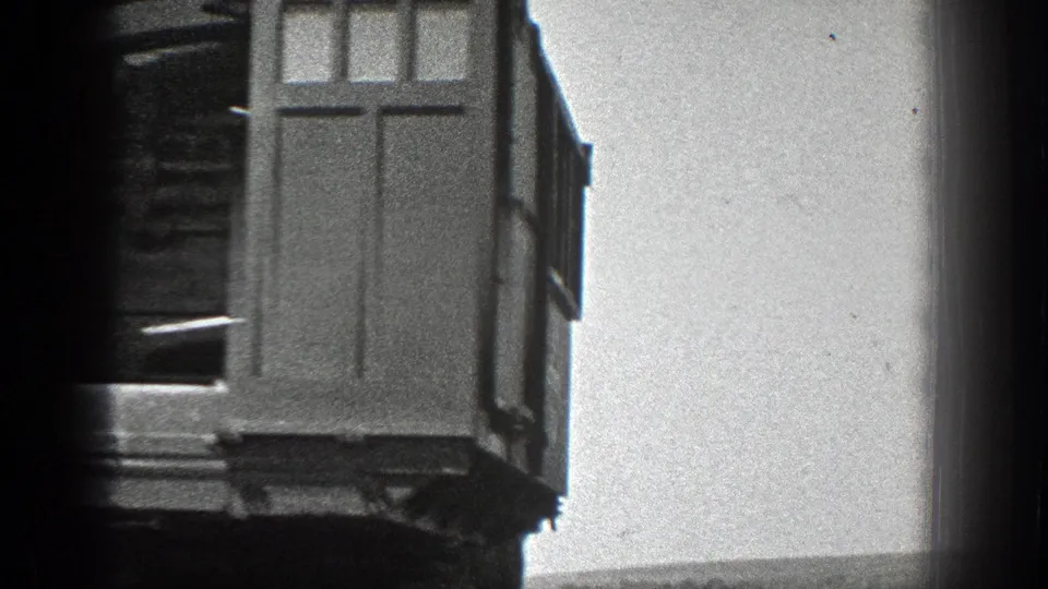 Close 8mm view of the crane's paneled side and open cab area, with soft focus and visible film-edge darkness.