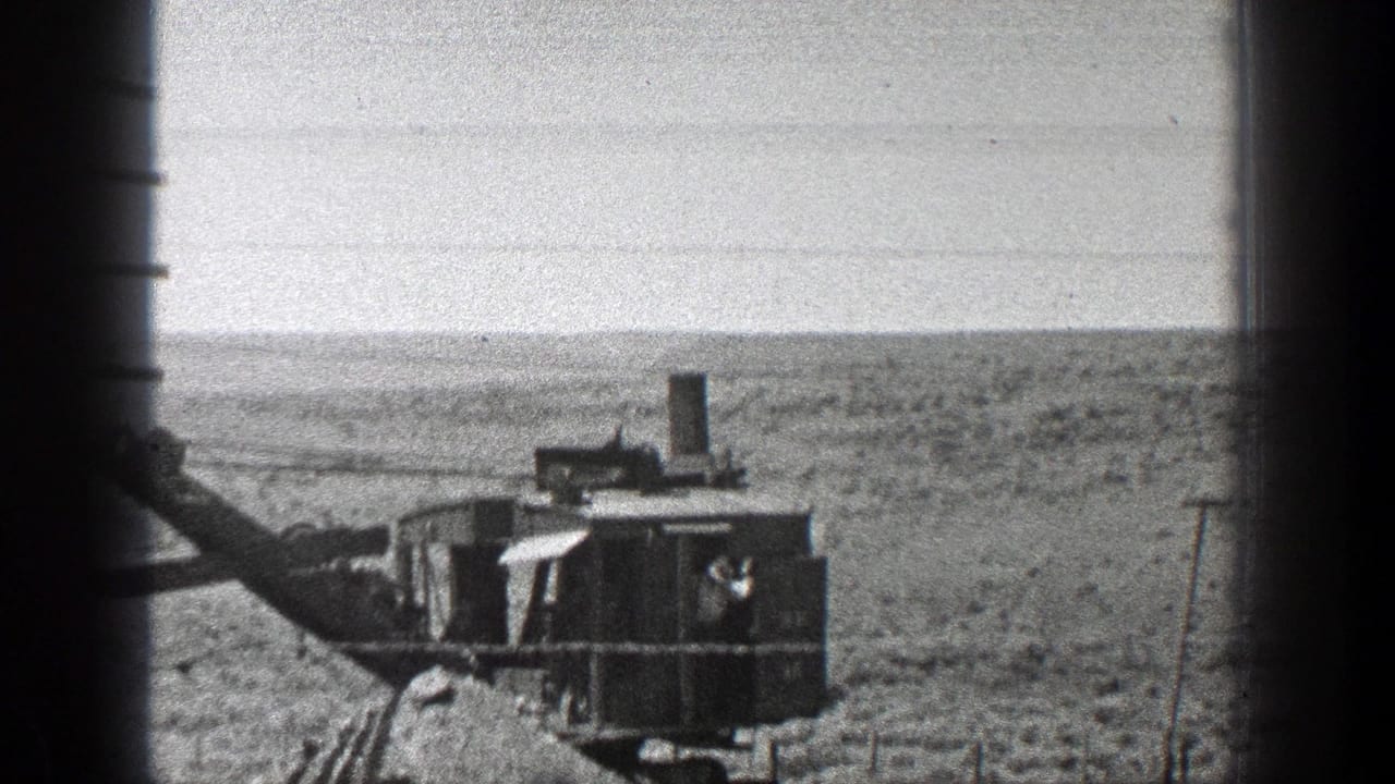 Earthmoving machine with boom and cab sits in a broad desert landscape.