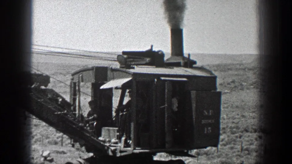 Closer 1936 California 8mm frame of the earth mover cab, smoke stack, and worker area, with dark framing along the sides.