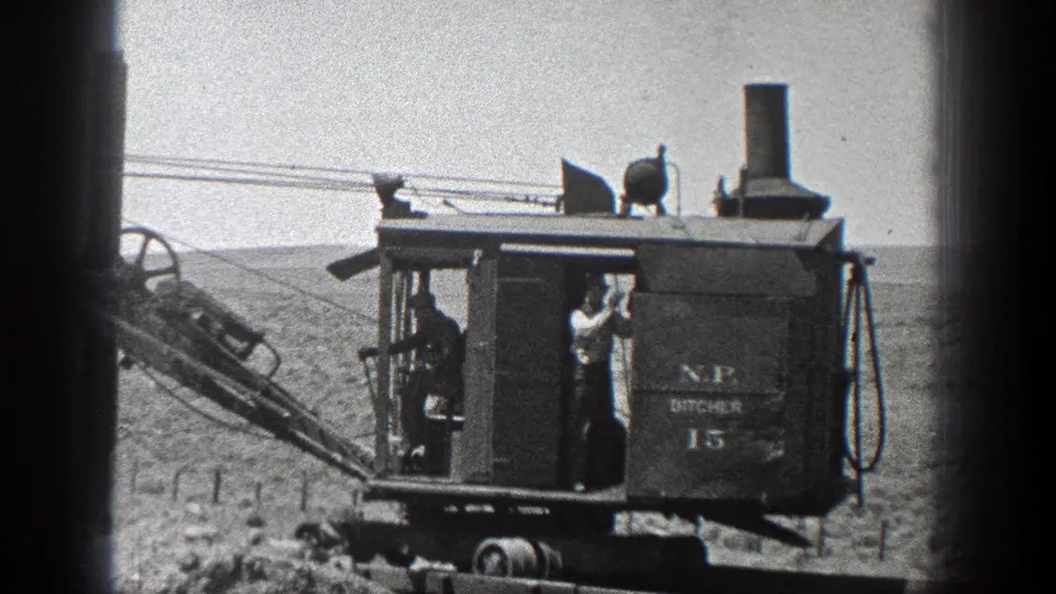 A worker stands on the platform of the N.P. DITCHER 15 in rural California footage from 1936.