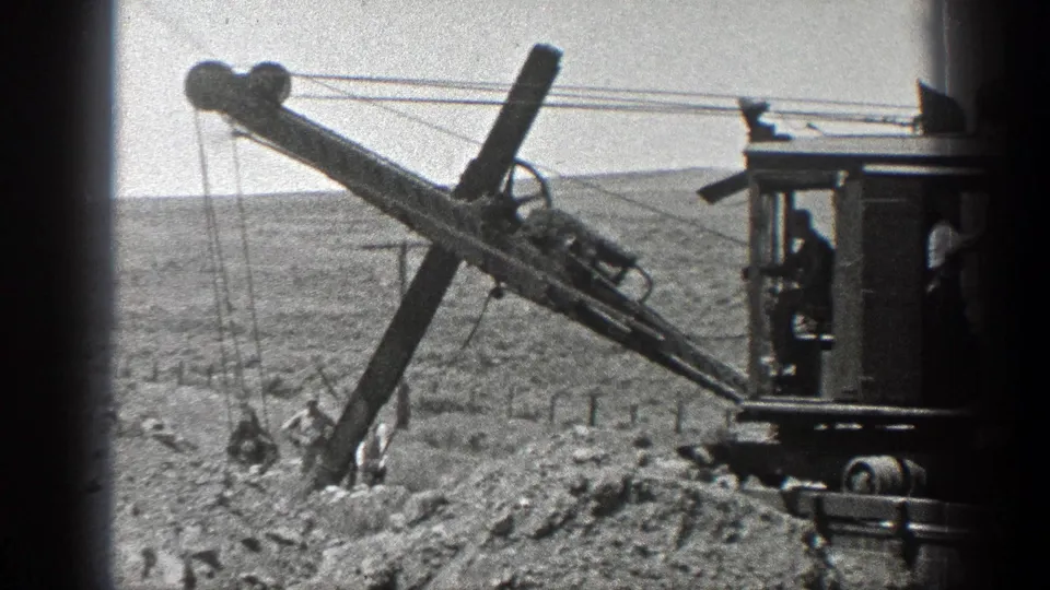 1936 California 8mm frame showing a steam-powered drilling rig near workers on a dry railroad construction site.