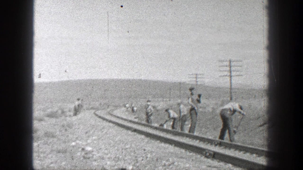 Adult workers maintain a railroad track in rural California, with utility poles and low hills visible in this 1936 8mm home-movie frame.