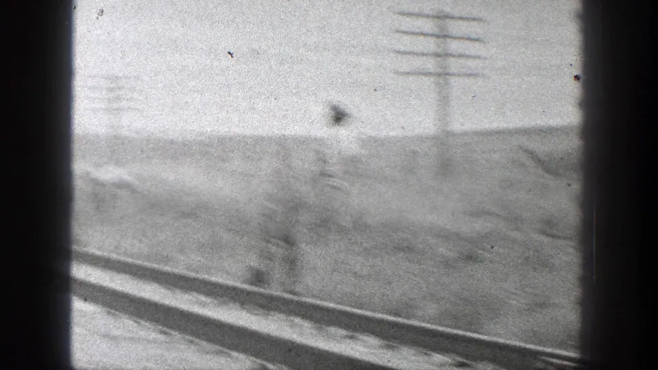 A blurred 8mm frame shows the rail line, utility poles, and rural California hillside as the camera moves past the scene.