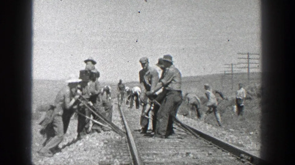 California 1936 home-movie frame showing a rail crew with hand tools beside tracks in a bright, dry landscape.