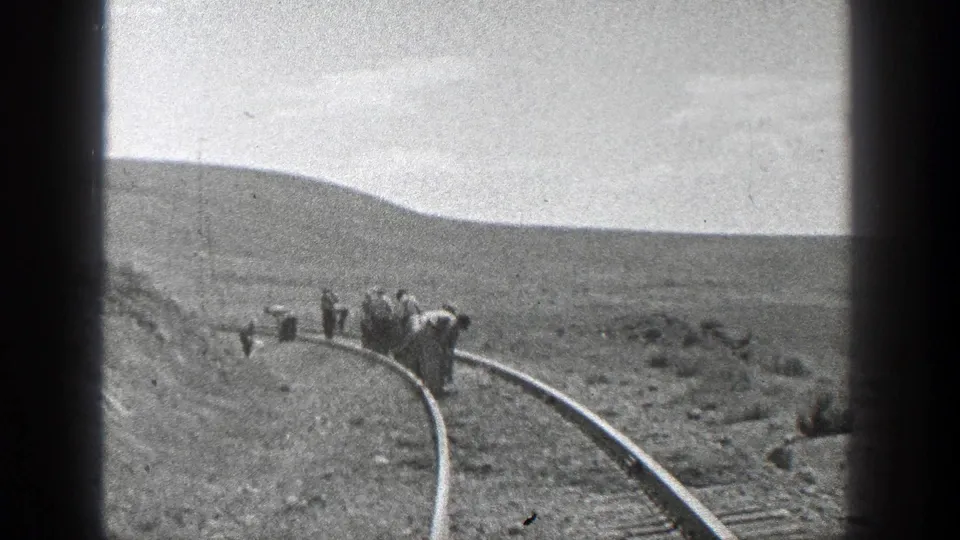 1936 California frame with several men walking and working along a curved rail line through sparse, dry terrain.
