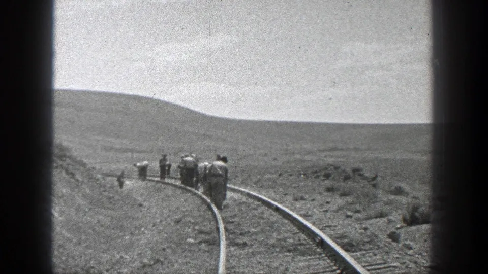 Wide 1936 California 8mm view of railroad workers along a bend in the track with hills and open scrubland beyond.