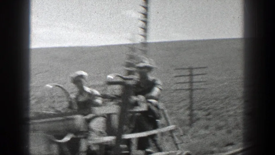 Soft, close 8mm frame of workers on a small rail cart passing utility poles in rural California in 1936.