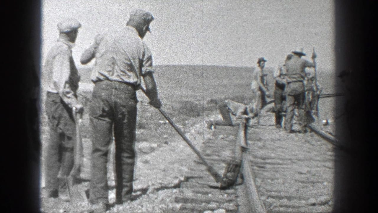 Several men gather along railroad rails with tools in hand.